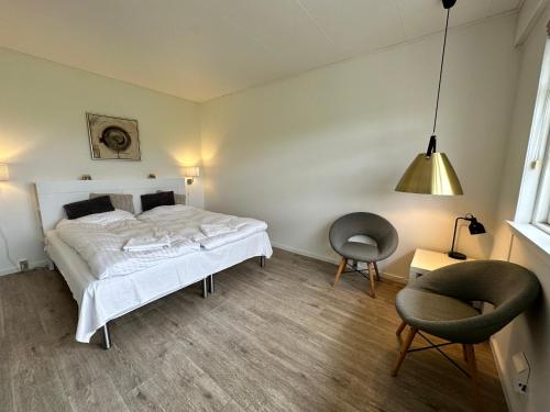 OrøOrø Kro & Hotel的一间卧室配有一张床、一把椅子和一盏灯