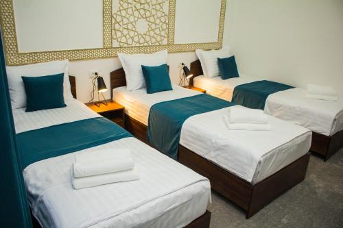 布哈拉Jahangir Boutique Bukhara的一间设有三张床的客房,配有蓝色和白色的床单