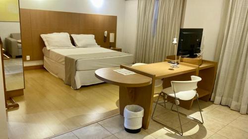 里贝朗普雷托Araucária Flat的酒店客房配有一张床铺、一张桌子和一张书桌。