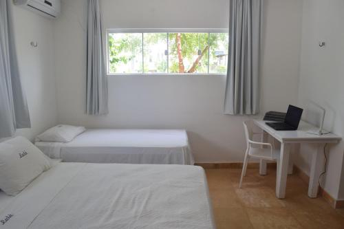 圣米格尔-杜戈斯托苏Casa de Lala Beach House的一间卧室配有两张床和一张带笔记本电脑的书桌