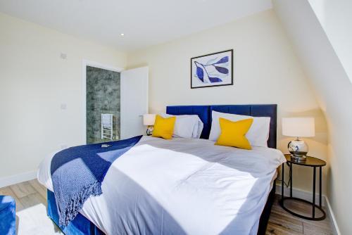 CheamHybrid Resi - Cheam, Sutton的卧室配有蓝色和白色的床以及黄色枕头