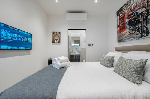 伦敦Luxurious Mews House Next to Hyde Park的卧室配有一张白色大床和电视。