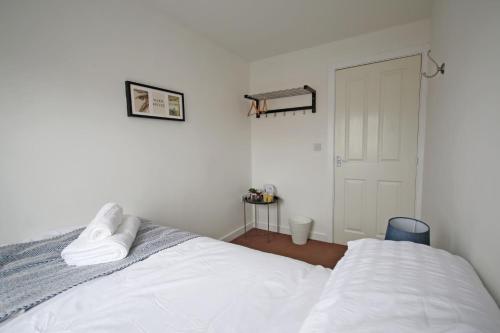朗伊顿4ft Double bed with Parking & Wi-fi in Modern Townhouse in Long Eaton的卧室配有带白色床单的床和门。