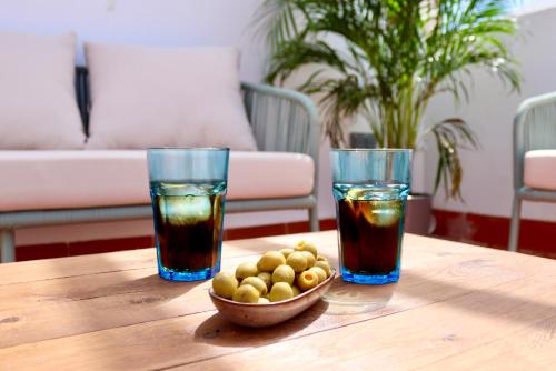 佩尼斯科拉La Plaza Hostal的木桌旁的两杯饮料和一碗橄榄