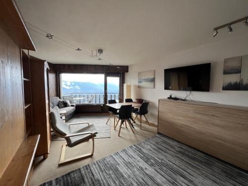 莱斯克伦斯Cosy Studio for 5 near ski lift, Les Gentianes的客厅配有桌椅和电视。