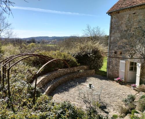 Sainte-Eulalie-dʼAnsLes Fleurs d'Ans的一座花园,花园内有石头建筑和一座石桥