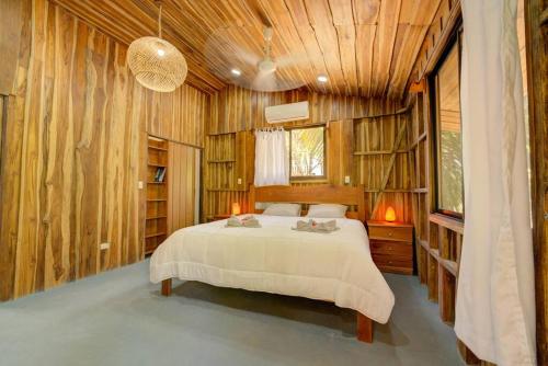 萨玛拉Sámara Tarantela Houses, Casa Bambú的卧室配有一张床铺,位于带木墙的房间内