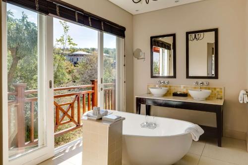 马加利斯堡Mount Grace Hotel & Spa的一间带浴缸和两个盥洗盆的浴室以及一个阳台