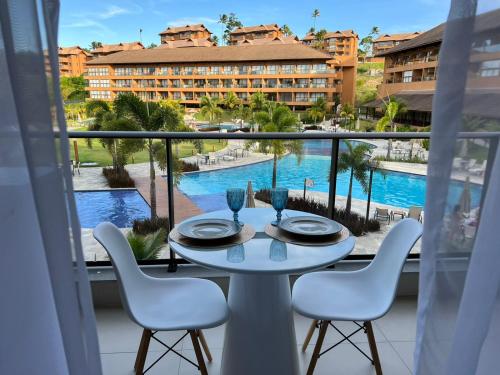塔曼达雷Flat com vista linda Eco Resort的阳台配有桌椅,享有泳池美景
