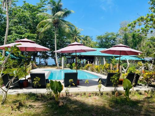 俊穆岛Koh Jum Delight Beach的一个带遮阳伞和椅子的游泳池以及一个度假村