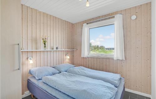 克利特默勒Pet Friendly Home In Thisted With Indoor Swimming Pool的一间卧室配有一张带蓝色床单的床和一扇窗户。