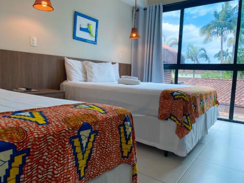 乌巴图巴Pousada Ubuntu的酒店客房设有两张床和窗户。