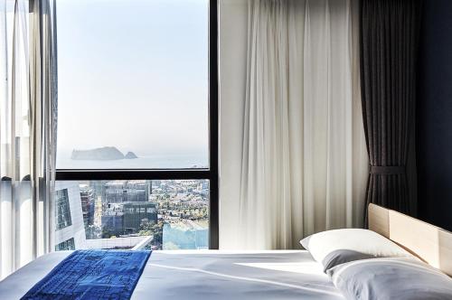 西归浦市Jeju Pureun Hotel的一间卧室设有一张床和一个大窗户