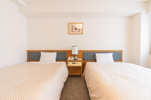 东京Forest Hongo by unito的两张睡床彼此相邻,位于一个房间里