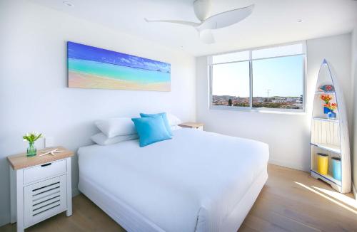 悉尼Bondi Aqua Vista - Walk to beach and shops的一间白色卧室,配有一张床和一个冲浪板