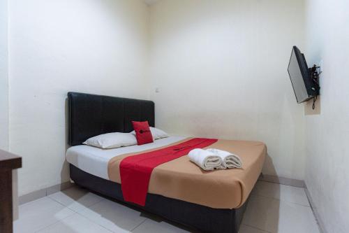 巴淡岛中心邦加拉亚街红门旅馆的一间小卧室,配有一张床和电视