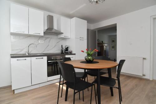 锡尼Apartman Gluić的厨房配有白色橱柜和木桌及椅子