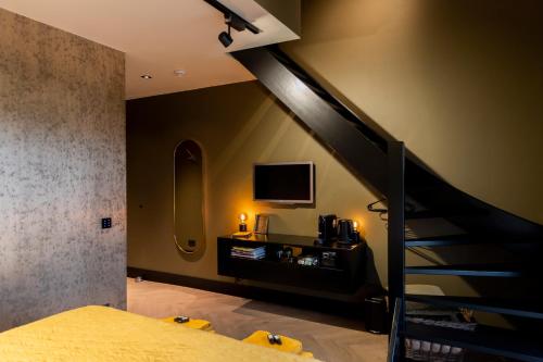 LangenboomBed en breakfast Suite 8的一间卧室设有楼梯、电视和床。