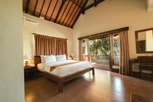 乌布Artini Bisma Ubud Hotel的一间带大床的卧室和一个阳台
