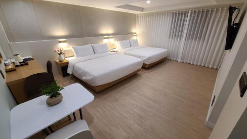 釜山Hotel Andrest的酒店客房设有两张床和一张桌子。