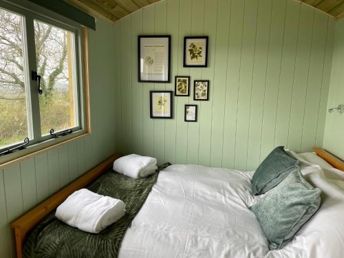 盖尔文Cosy Shepherd Huts near Newborough Forest Anglesey的一间卧室配有带两个枕头的床和窗户