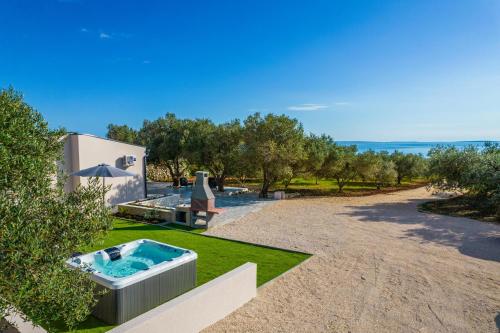 诺瓦利娅Villa Grioni, beach front villa with jacuzzi的后院,在草地上设有热水浴池