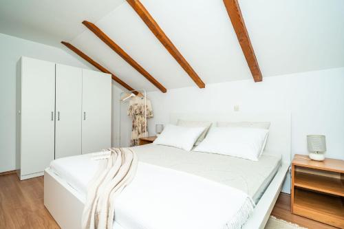 默克斯卡Apartment Sunday的白色的卧室设有白色的床和木制天花板