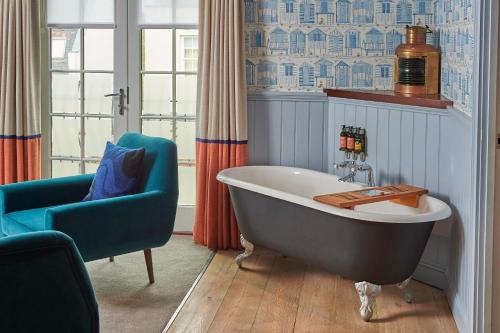 浦耳普尔酒酒店的一间带爪足浴缸和蓝椅的浴室