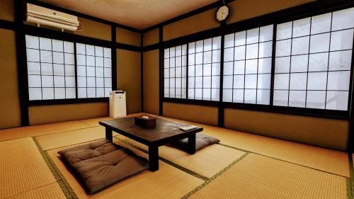 富士吉田市富士吉田たまきや的窗户前配有桌子和沙发的房间