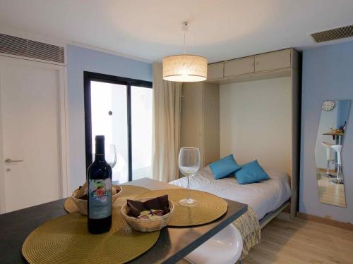 圣罗克Lightbooking Royal Golf Sotogrande的一间设有一张床和一张桌子及一瓶葡萄酒的客房