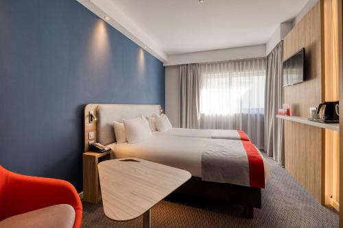 梅赫伦梅赫伦市中心快捷假日酒店的酒店客房,配有一张床和一张红色椅子