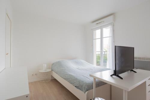 布西圣乔治PARIS-DISNEY - STUDIO 1 MIN GARE的白色卧室配有一张床和一张书桌上的电视