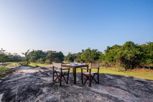 雅拉Wild Trails Yala by Suri的一张桌子和两把椅子,坐在岩石上