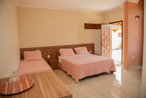 蒙蒂锡昂Pousada Mirante das Águas的一间卧室配有两张床、粉红色的床单和桌子