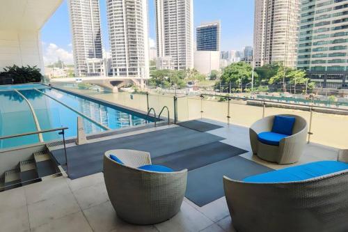 马尼拉Aveline Suites Cozy Skyline View ACQUA Private Residences near Rockwell Makati的一个带椅子的阳台和一个位于大楼内的游泳池