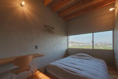 熊本YHouse的一间卧室配有一张床、一张书桌和一个窗户。