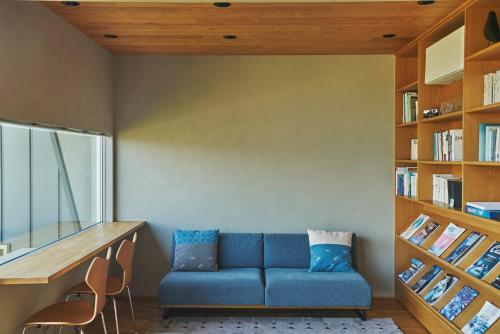 熊本YHouse的客厅配有蓝色的沙发和书架