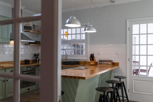 大里贝拉Casa da Praia dos Moinhos的厨房配有绿色橱柜和带凳子的台面