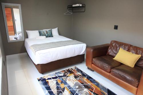 Pimville4447 Guesthouse的一间卧室配有一张床和一张皮沙发