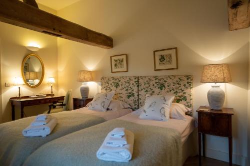 AldebyStackyard Lodge - enchanting 18th Century converted barn in the Waveney Valley的客房内的两张床和毛巾