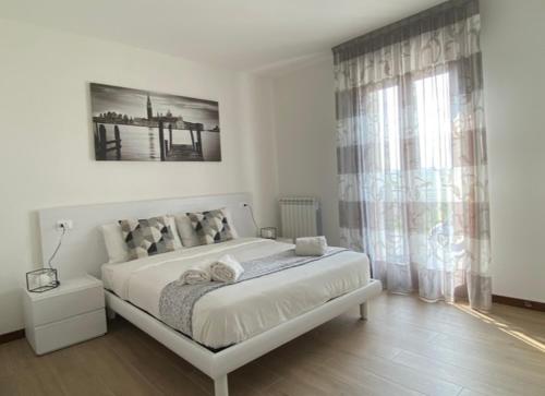 皮亚韦河畔诺文塔Residence Outlet Vivaldi的白色的卧室设有一张大床和一个窗户