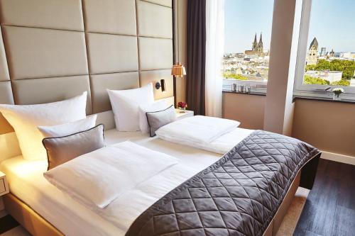 科隆科隆施泰根博阁酒店的酒店客房设有一张带大窗户的床。