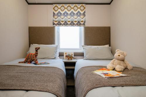 帕兹托Bailey Lodge的坐在一个房间里两张床上的泰迪熊