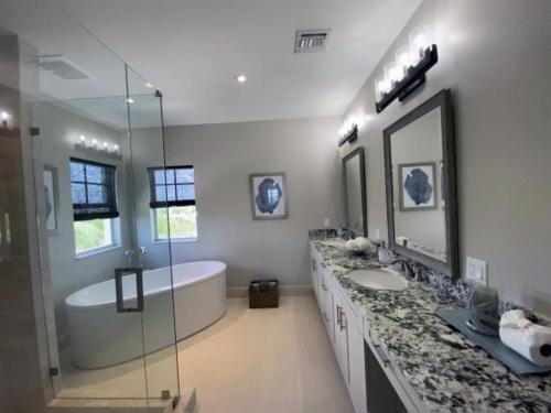 基拉戈Hideaway - 3br-2,5ba的浴室配有2个盥洗盆、浴缸和淋浴。