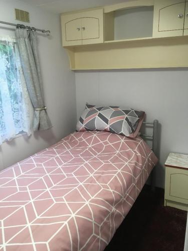 海尔The Caravan at Loggans Lodge的卧室配有粉红色的床和窗户。