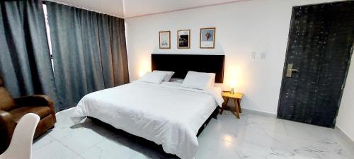 麦德林HOTEL A & A SANTA ALEJANDRIA的卧室配有白色的床和椅子