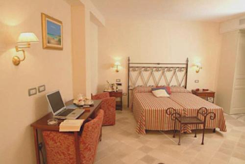 奥斯图尼黎莱斯盛特利吉欧酒店的一间卧室配有一张床和一张带笔记本电脑的书桌