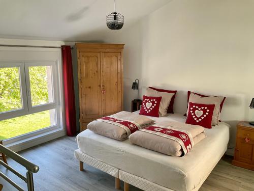 ScherwillerGite Au sauna de l’Aubach的一间卧室配有红色和白色枕头的床
