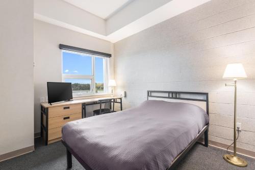 汉密尔顿汉密尔顿会议中心公寓酒店 的一间卧室配有一张床和一张书桌及电视