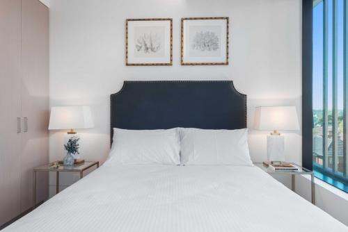 墨尔本Chic St Kilda Retreat, Close to Beach & Eats的一间卧室配有一张带两盏灯的大型白色床。